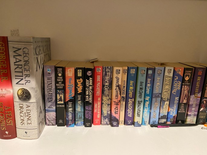 Photograph of books by Anne McCaffrey among other authors on my bookshelf